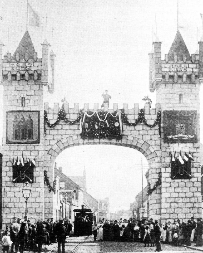 1893 De oudst bekende afbeelding van de stoomtram door de Gasthuisstraat. De erepoort was opgericht ter gelegenheid van het 50-jarig bestaan van de Nieuwe Koninklijke Harmonie.
